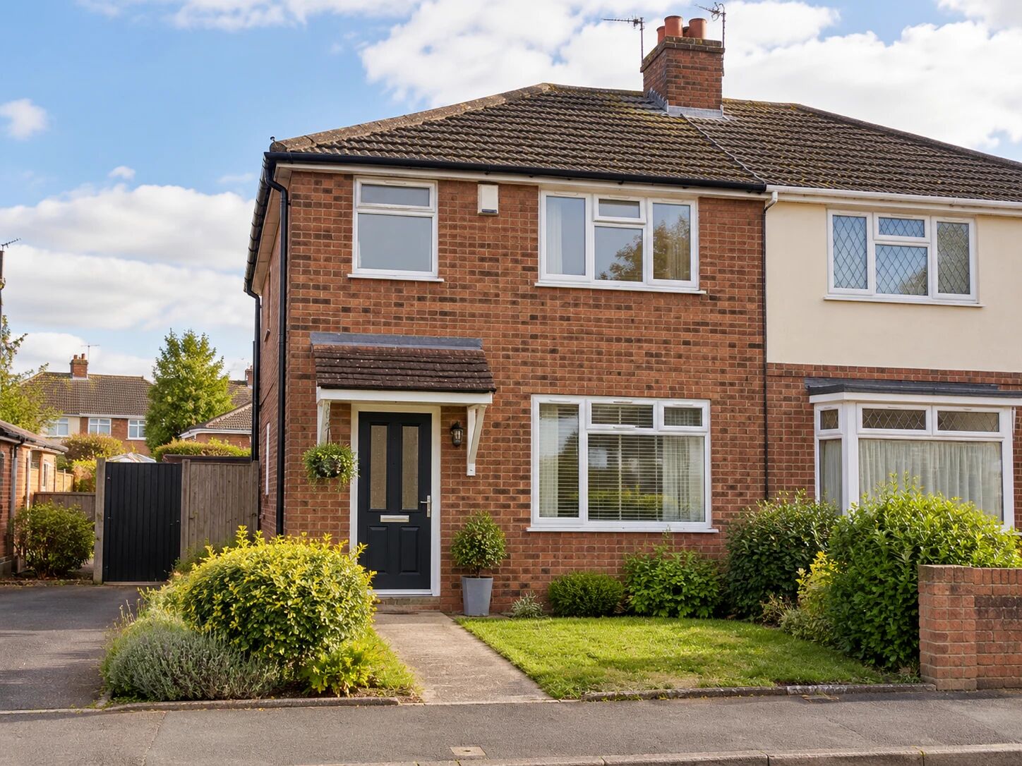 A well-kept red-brick semi-detached home with a front garden