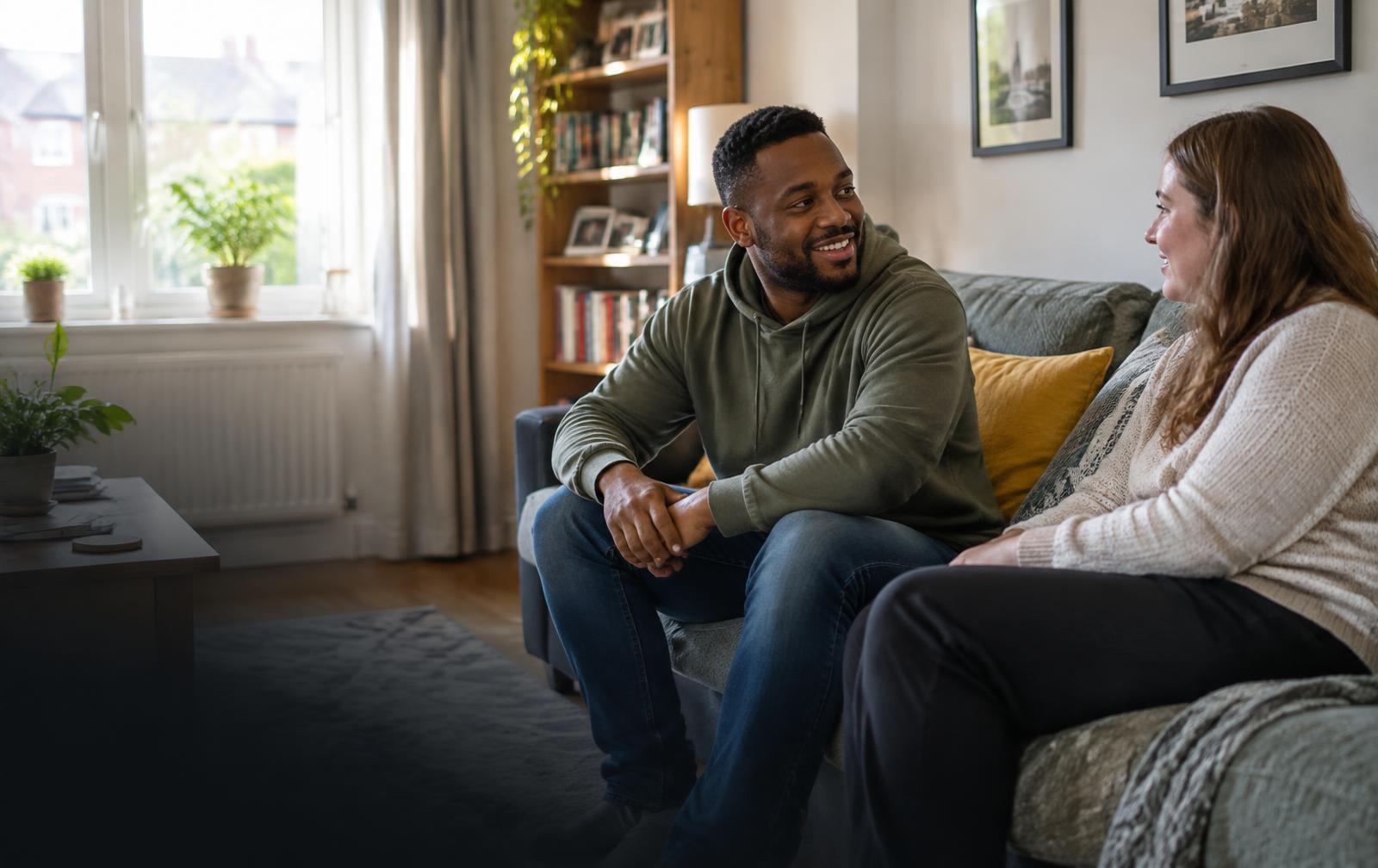 Two adults having a relaxed conversation in a bright UK living room